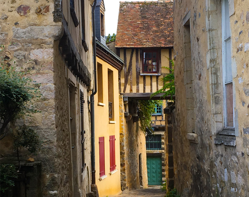 Un hommage à Robert Doisneau qui est venu au Mans pour prendre des photos et a vu un ours en peluche dans cette vitrine ! Ours en peluche fait des vagues depuis la fenêtre d'une maison à colombages dans une rue pavée du Mans