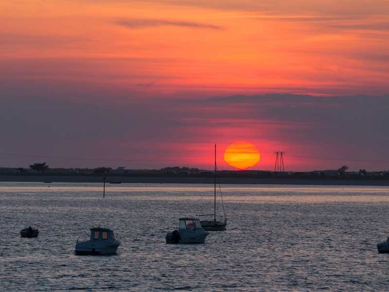 Vue sur la mer au coucher du soleil, petits bateaux flottant, dans la ville balnéaire de Carnac Plage, Bretagne