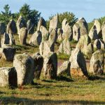Close up of standing stones in Carnac, boulders worn by weather, grass growing at their bases