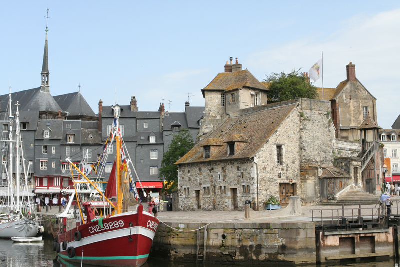 Bateau dans le port de Honfleur, Normandie, de vieux bâtiments en pierre l'entourent