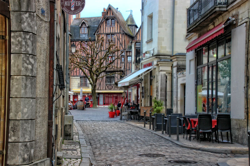 Rue pavée avec tables et chaises sur le trottoir pour dîner en plein air à Tours, Val de Loire