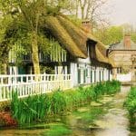 Very pretty half-timbered house with a river running alongside filled with reeds and water plants, Veules