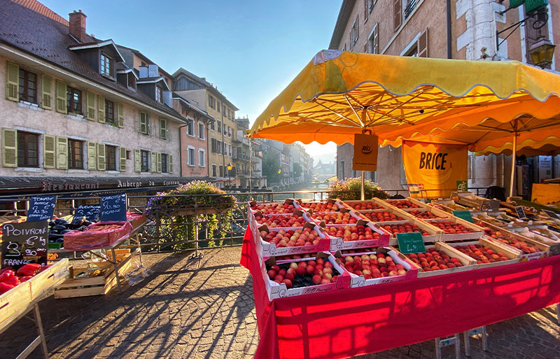 Marché d'Annecy Étal de fruits sur un marché sur un pont pavé au-dessus d'un canal à Annecy