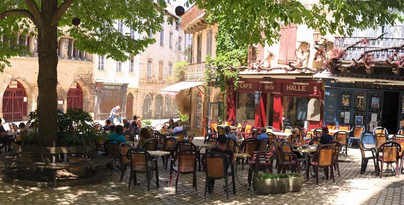 Des gens assis à la terrasse d'un café par une journée ensoleillée à l'ombre des platanes
