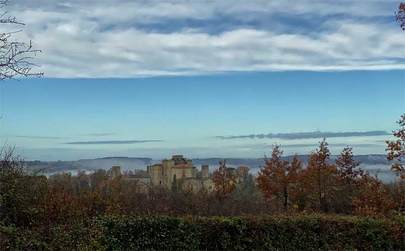 Vue sur la campagne jusqu'à une petite ville fortifiée, ses tourelles et ses tours au sommet d'une petite colline