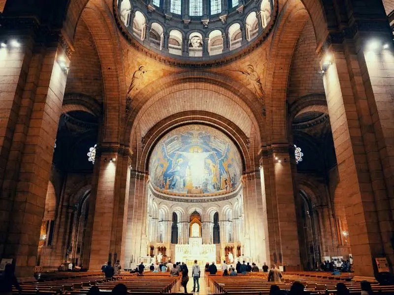 Intérieur de l'église du Sacré-Cœur de Paris, coupoles baignées de lumière et une immense mosaïque au plafond