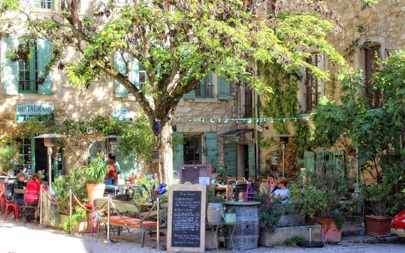 Des gens assis à une terrasse de café ombragée par des arbres, Oppède-le-Vieux, Provence