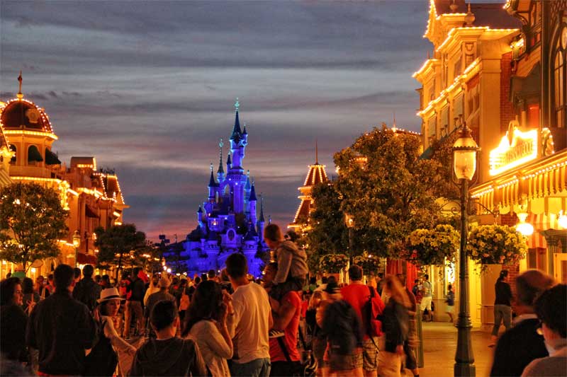 Main Street Disneyland Paris la nuit La rue principale illuminée de Disneyland Paris la nuit, de nombreuses personnes marchent dans la rue