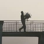 Man crossing a drawbridge at the Castle of Chenonceau carrying a bouquet of flowers