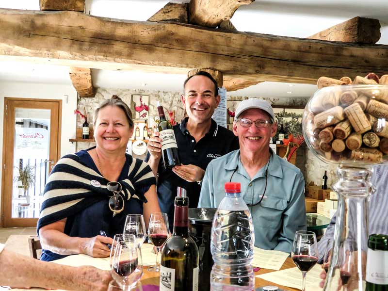 Deux hommes et une femme montrant des bouteilles de vin dans un vignoble