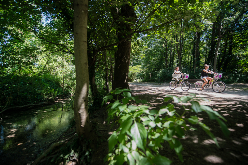 Balade à vélo le long du canal de Valence Photo © Cyril Crespau Valence Romans Tourisme Une femme et une fille font du vélo sous un auvent de feuilles vertes le long d'un canal