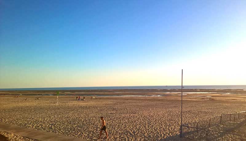 Un homme marche sur une plage de sable immaculée alors que le soleil se couche à Le Touquet-Paris-Plage, dans le nord de la France