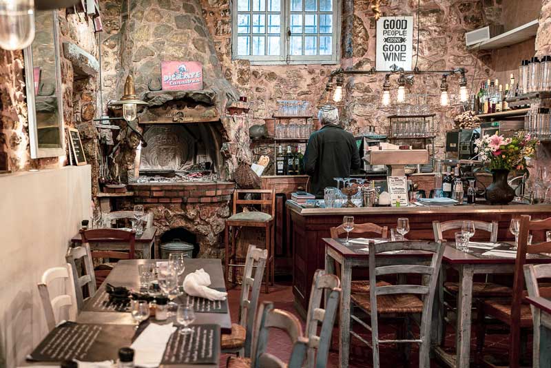 Salle à manger d'un restaurant de style rustique avec murs en pierre et chaises et tables en bois