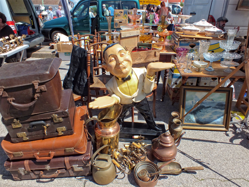 Un assortiment d'objets d'occasion comprenant une statue de serveur en bois et des antiquités dans un marché aux puces en France