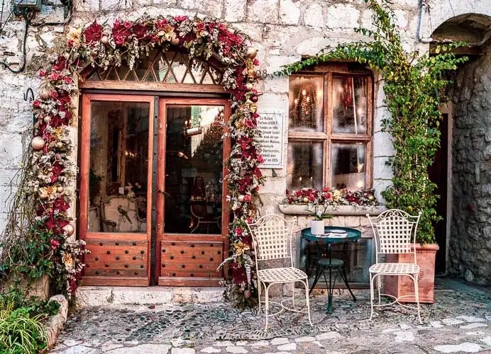 Café en terrasse avec des roses accrochées autour de la porte à Saint-Paul-de-Vence, Provence