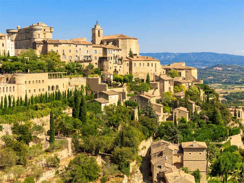 La Provence de Gordes coule de son perchoir escarpé Ville perchée de Gordes en Provence, les bâtiments s'accrochent à une falaise abrupte entourée de vignobles