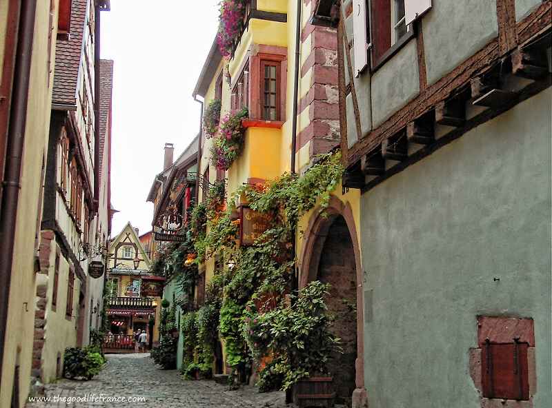 Route sinueuse à Riquewihr pleine de belles maisons de toutes les couleurs vue de la rue de Riquewihr