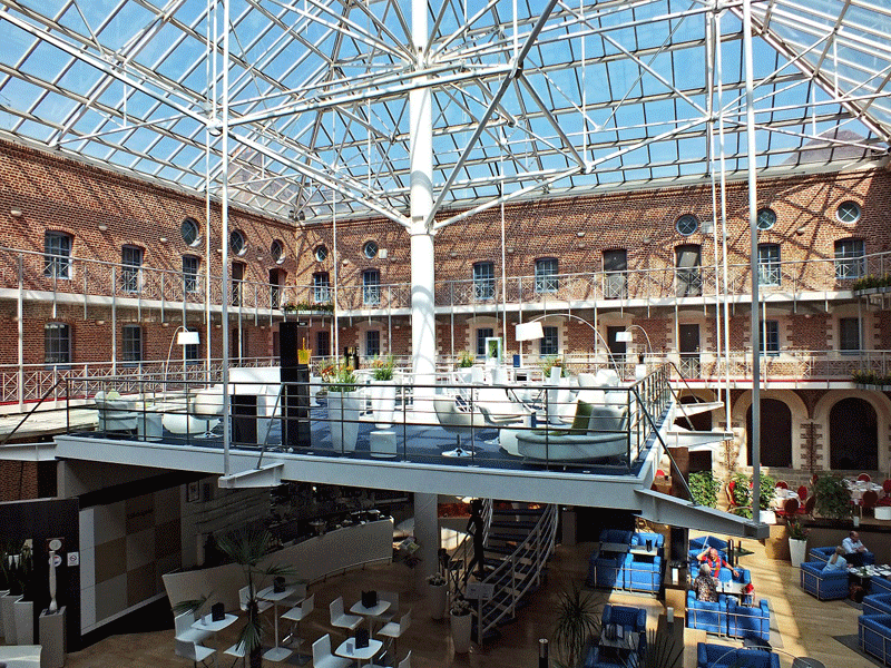 Bar à champagne vitré suspendu sous une verrière recouvrant une cour d'une abbaye de Lille