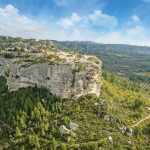 View of Les Alpilles, Provence from the sky, a rocky outcrop in a sea of vineyards and forests