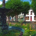 Pretty fountain in a town square in Montreuil-sur-Mer, surrounded by plants and trees