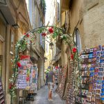 A narrow street lined with ancient buildings made into quirky, colourful shops in Montpellier