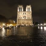 Notre Dame Cathedral at night, the iconic bell towers lit up against a dark sky