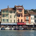 Cassis harbour lined with pastel coloured buildings and colourful shops
