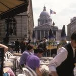 Waiter carries tray to a table in a Paris street