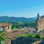 View over the roof tops of Vaison-la-Romaine with mountains in the distance under a blue sky