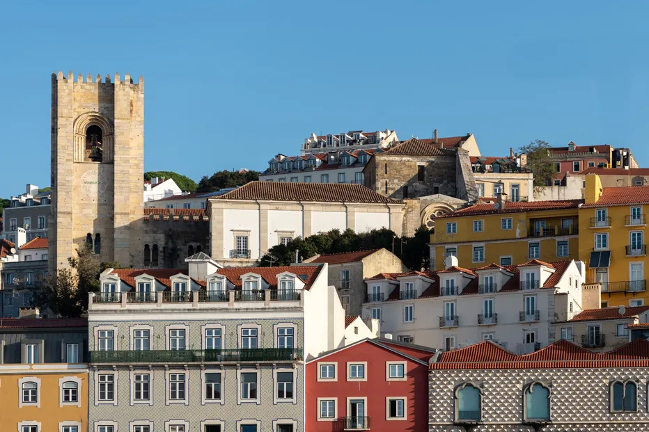 Prédios em Lisboa ao sol, com uma torre de igreja em destaque